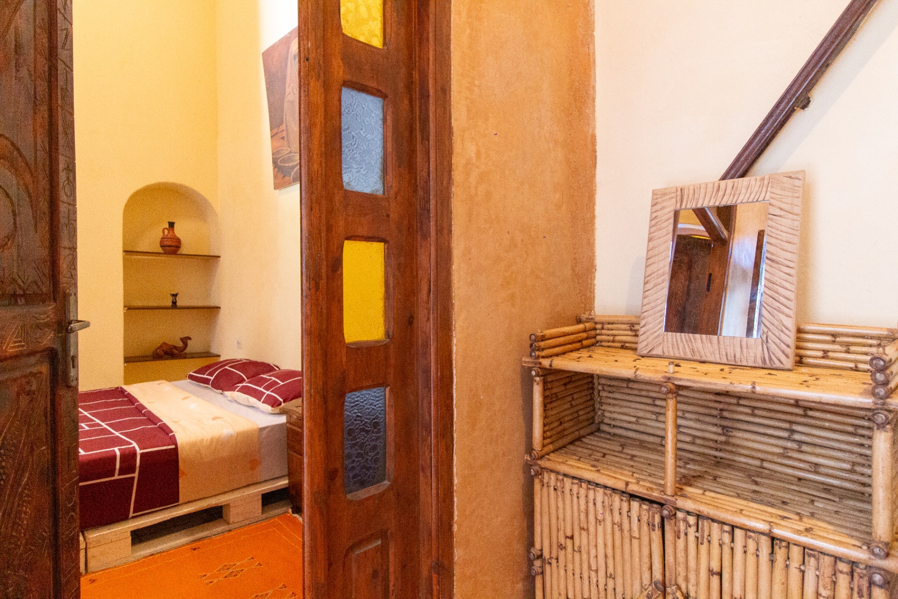 La Desert Room du Chill Art Hostel, une chambre double privée aux murs sable et ocre, avec une tête de lit en bois sculpté