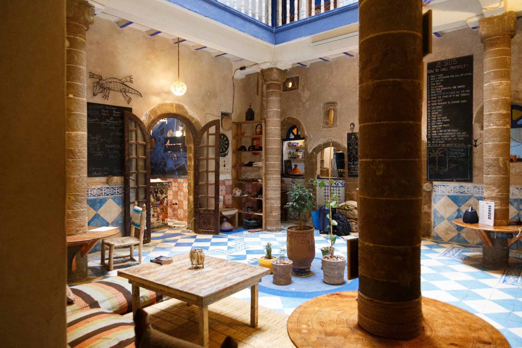 Le salon du Chill Art Hostel: canapés, fresques murales, jeux de société et bibliothèque de voyage dans une maison de la médina