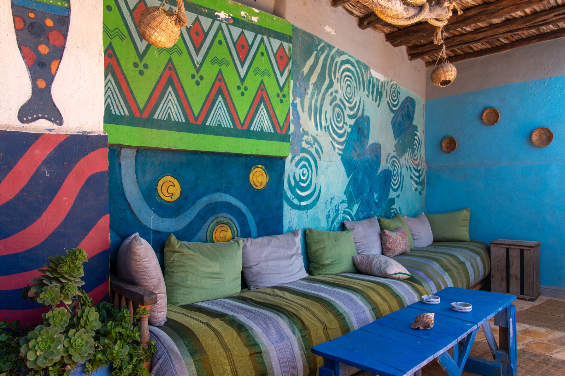 Coin détente du rooftop avec fresques et banquettes au Chill Art Hostel, médina d'Essaouira