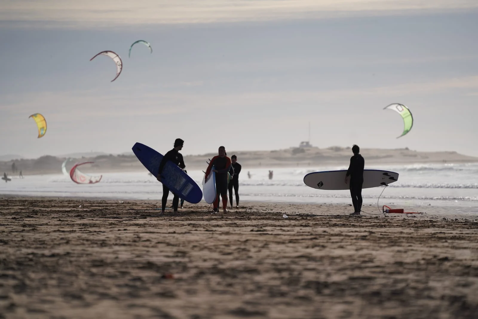 Surfeur au coucher du soleil sur la plage d'Essaouira, remparts de la médina en arrière-plan
